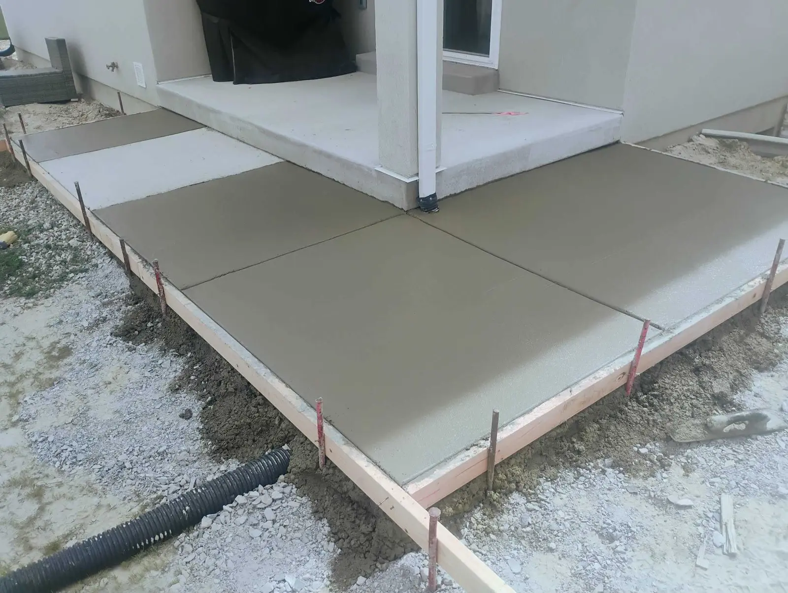Fresh concrete patio formed around a covered porch
